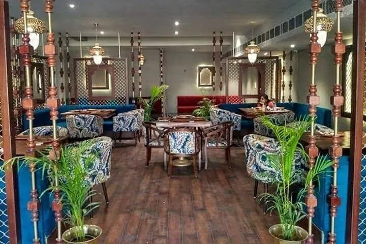 Blue sofa seating, patterned chairs and potted palms at Govindam Retreat Jaipur