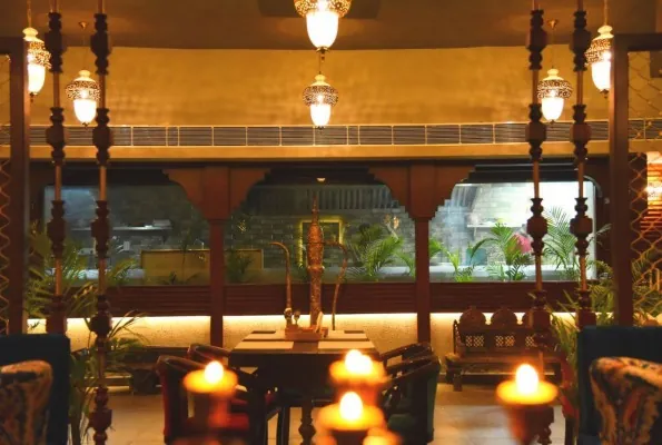 Candle lit table between carved pillars at Govindam Retreat in the evening