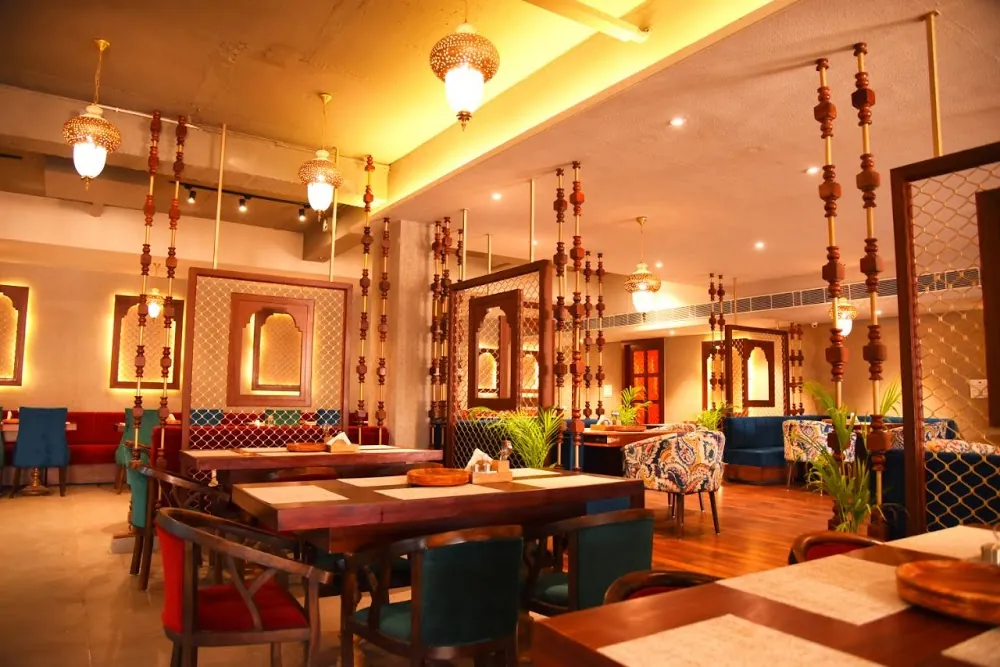 Govindam Retreat dining hall with brass lanterns, carved wooden pillars and jharokha frames