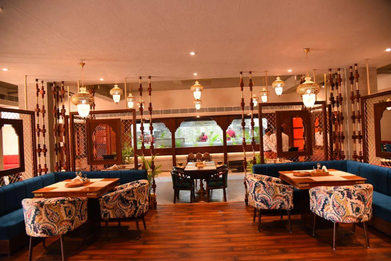 Paisley armchairs and blue sofas facing the open kitchen window at Govindam Retreat