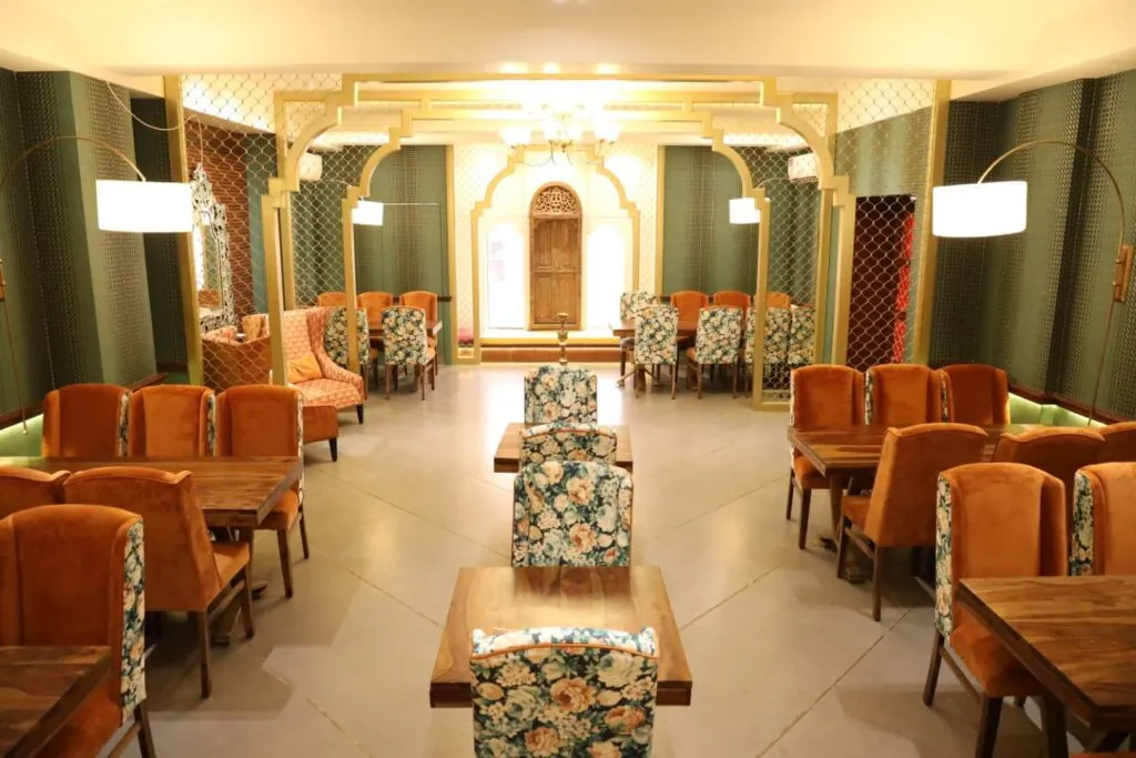 Govindam Retreat party hall with gold arches, orange chairs and floral upholstery