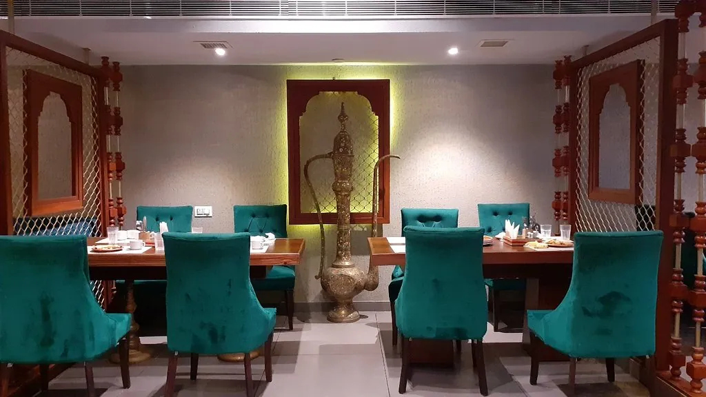 Private table at Govindam Retreat with teal velvet chairs and a brass jug in a lit niche